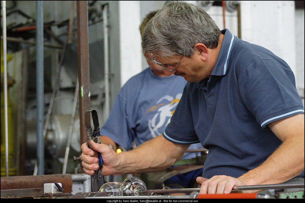 20060809_IMG_glas_24.JPG - Geschick und genaues Arbeiten ist notwendig, um den Glasstiel aus dem noch gl�hend heissen Glas ziehen zu k�nnen - Spiegelau, Bayern